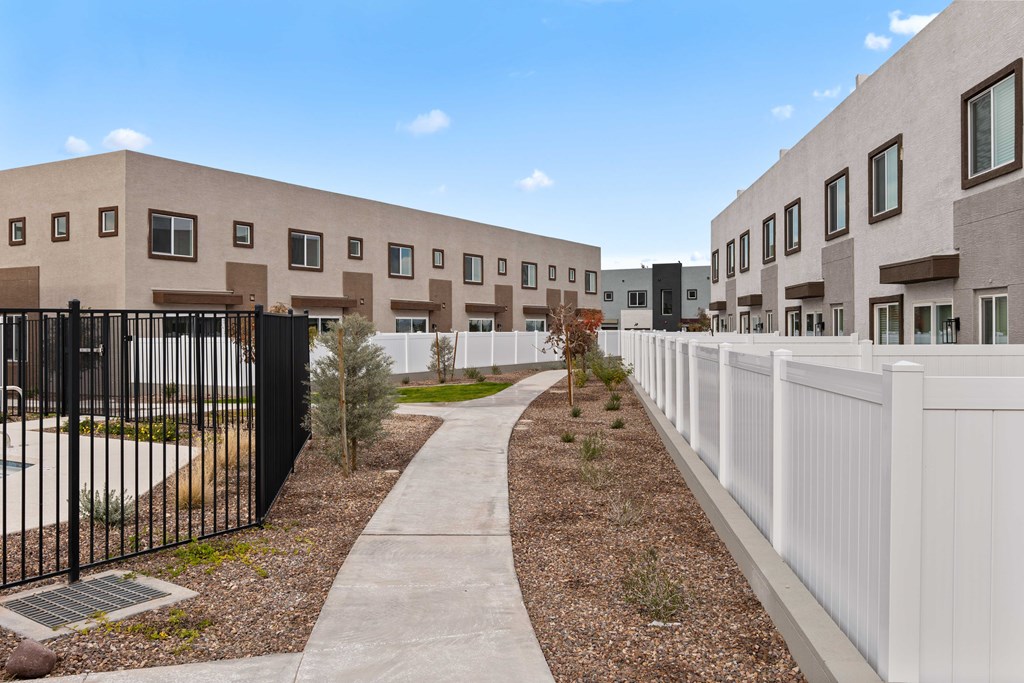 A modern building complex with a white fence and a walkway in the foreground.