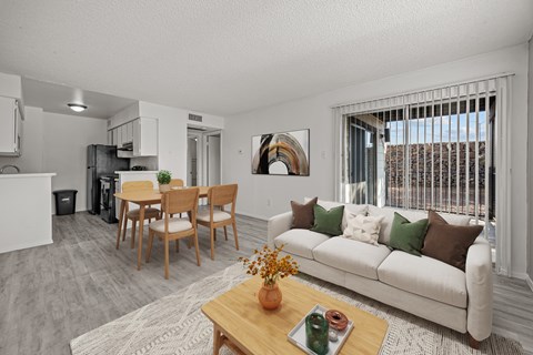 A living room with a white couch, wooden chairs, and a coffee table with a vase of flowers on it.