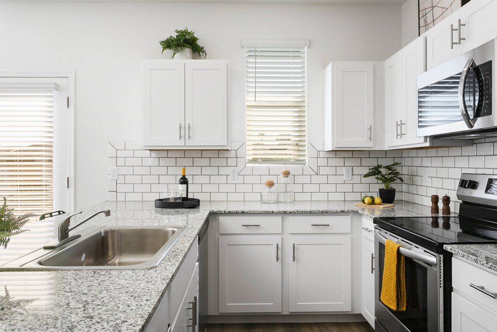 a kitchen with white cabinets and granite counter tops and a sink