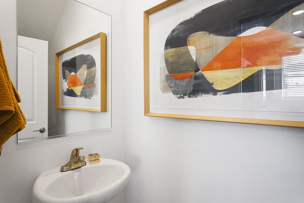 two paintings and a sink in a bathroom with a mirror