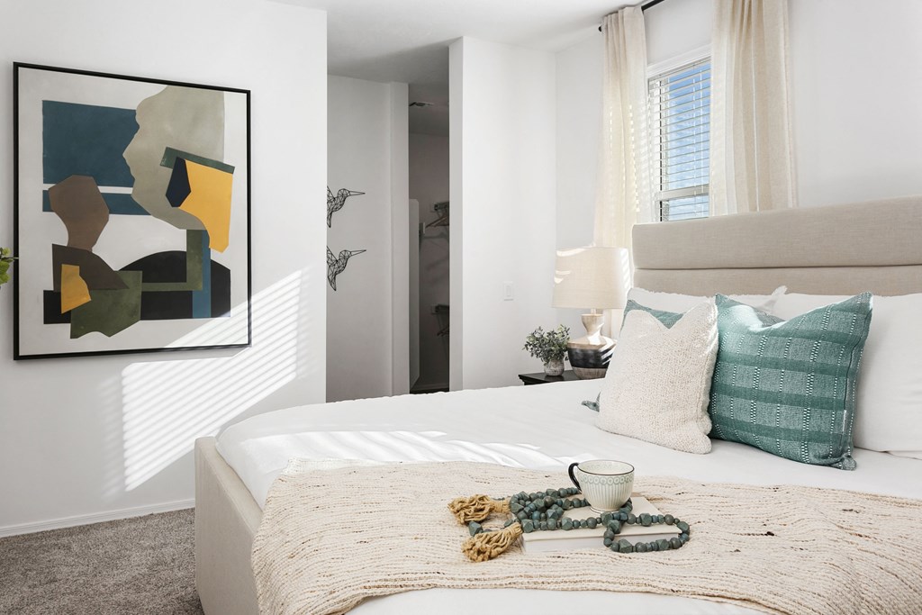 a bedroom with a bed and pillows and a painting on the wall