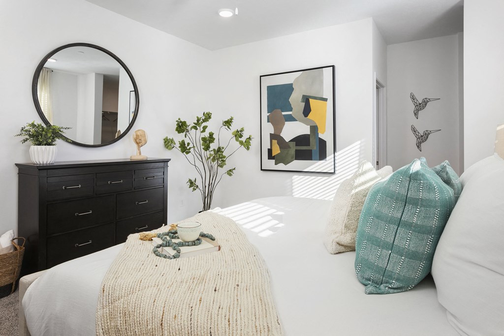 a bedroom with a white bed and a round mirror