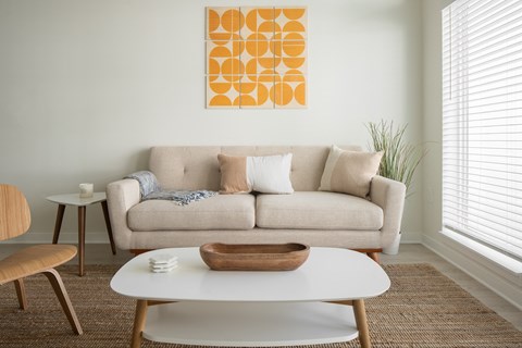 A living room with a couch, a chair, a coffee table, and a painting on the wall.