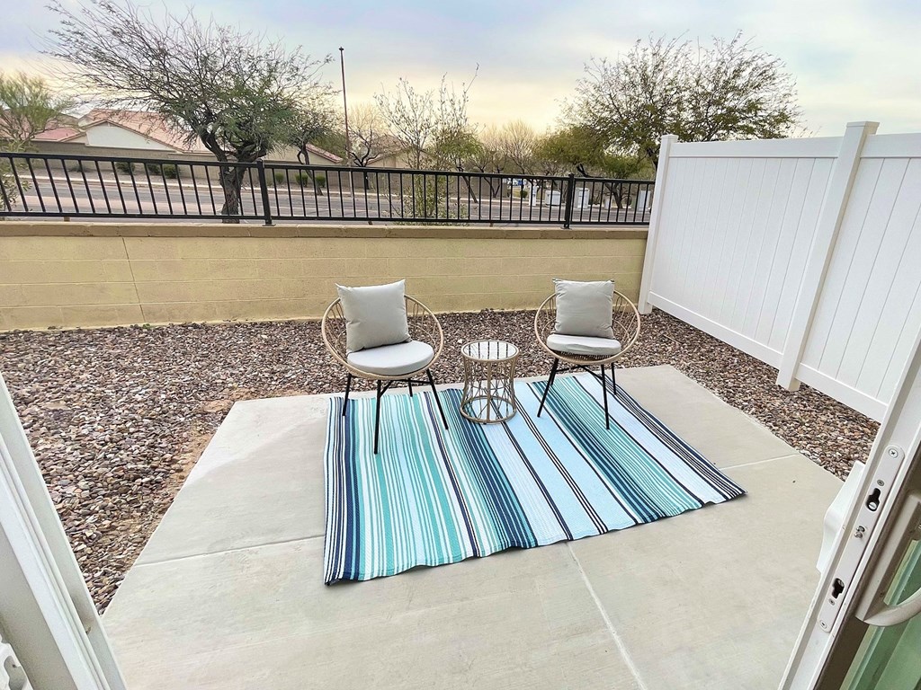 a patio with two chairs and a table on a rug