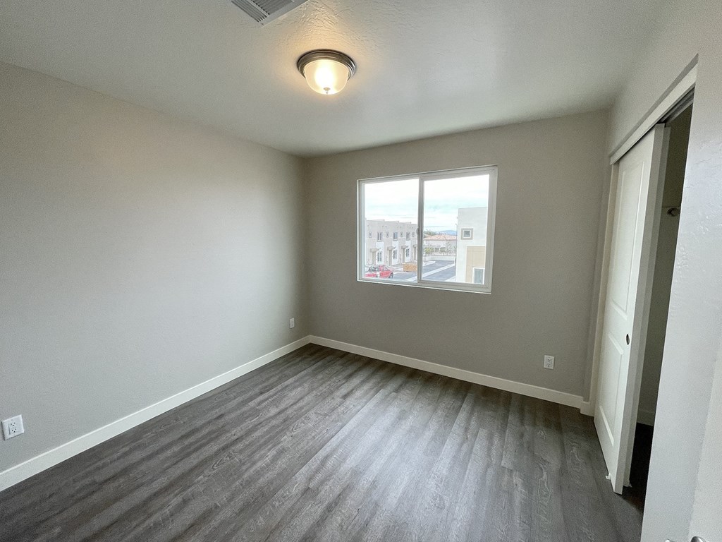 an empty living room with wood flooring and a window
