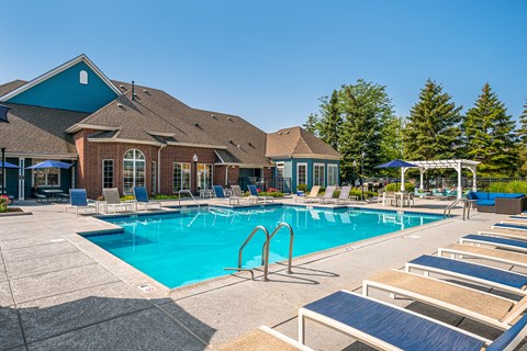 A large swimming pool with lounge chairs and a building in the background.