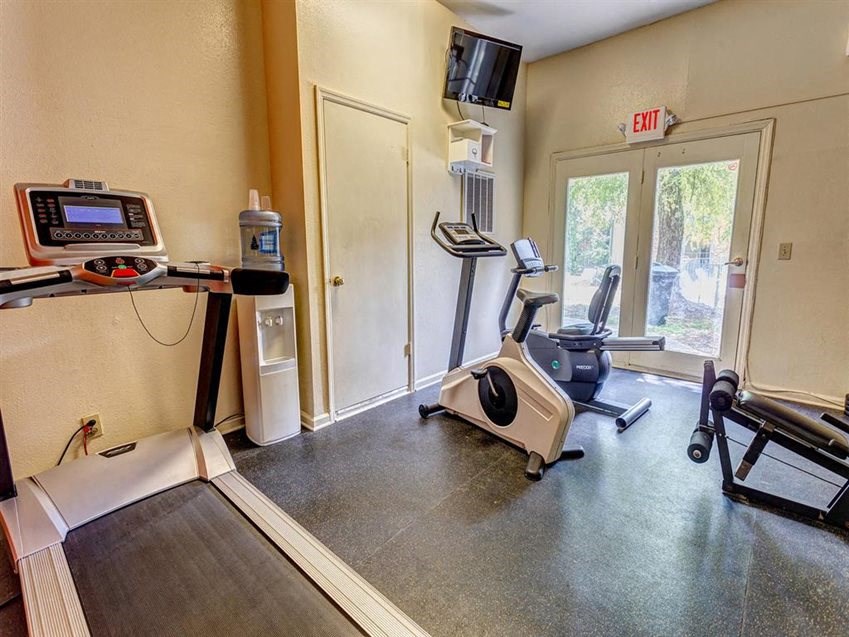 the gym is equipped with cardio equipment and a tv