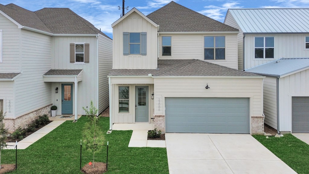 A house with a grey garage door is in front of other houses.