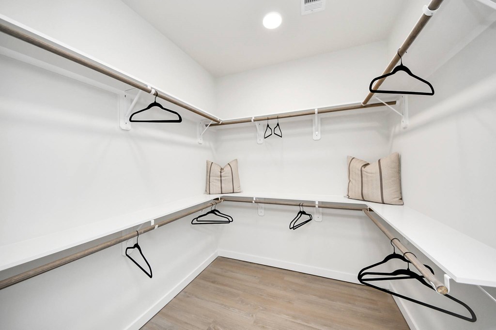 A walk in closet with clothes hanging on hangers.