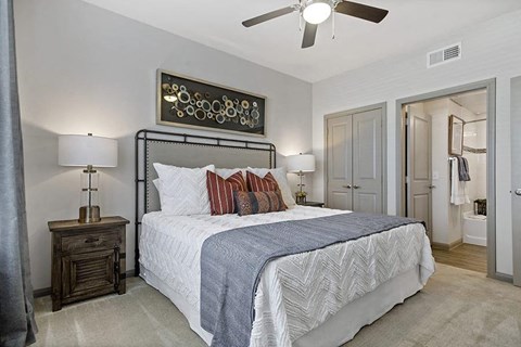 A bedroom with a large bed and a ceiling fan.