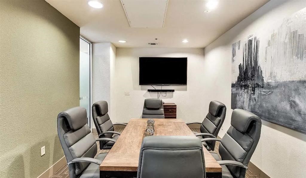 a conference room with a table and chairs and a television
