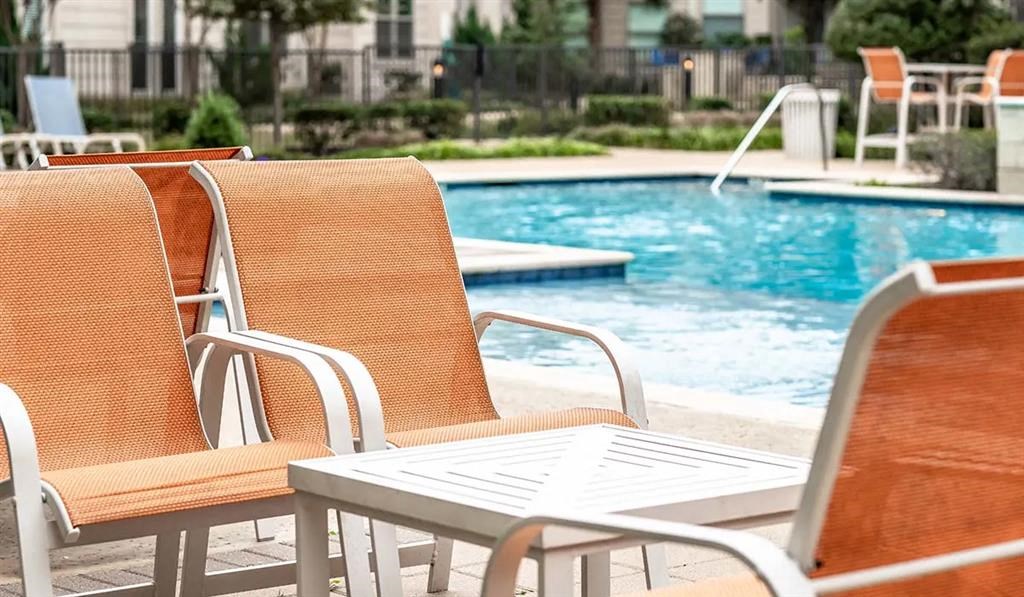 two chairs and a table next to a swimming pool