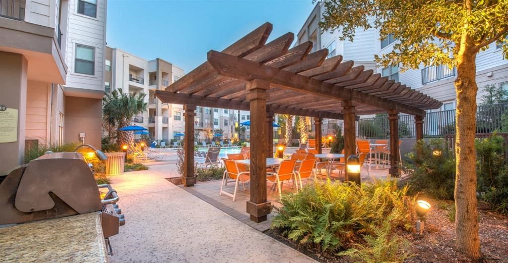 a patio with a pergola and a table and chairs