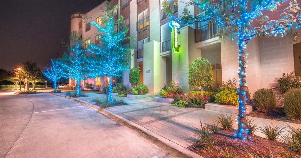 an apartment building at night with blue lights on the trees