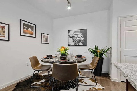 A dining room with a table set for four and a cowhide rug.