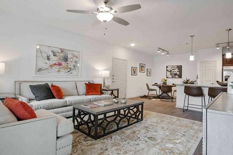 A living room with a white couch, a coffee table, and a painting on the wall.