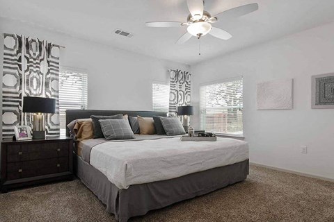 A bedroom with a large bed and a ceiling fan.