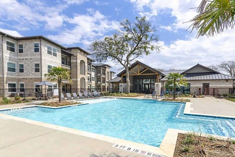 A swimming pool in front of apartment buildings with a sign that says