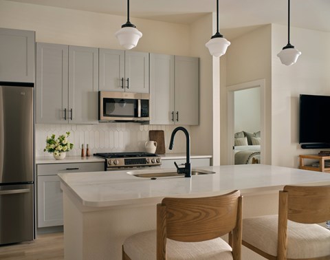 A kitchen with a white countertop and wooden chairs.