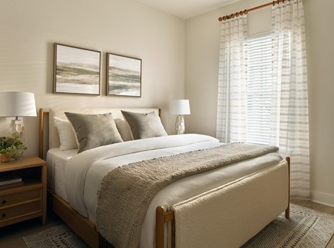 A bedroom with a large bed, two lamps, and two pictures on the wall.