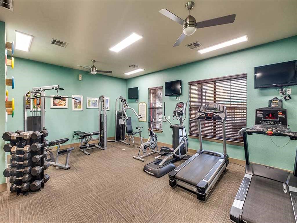 a gym with a lot of exercise equipment and a tv