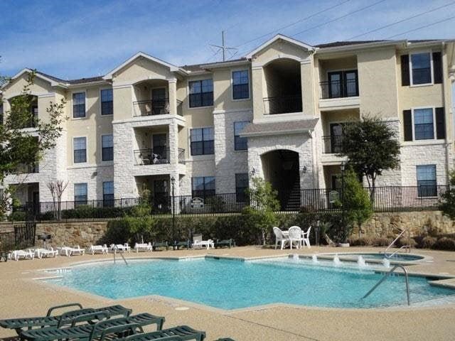 an apartment building with a large pool and chairs