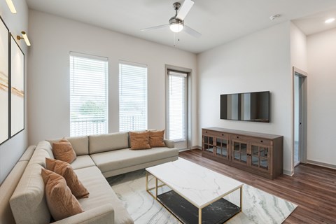 A living room with a grey couch, a white coffee table, and a television on a wooden stand.