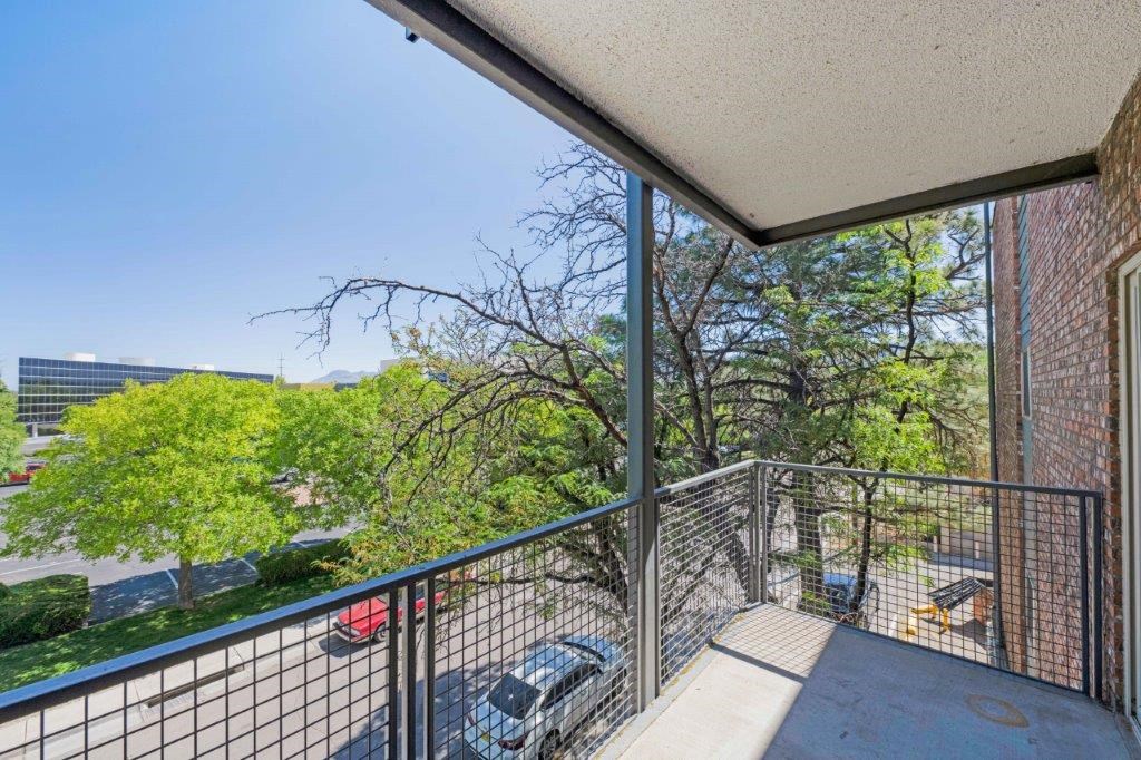 a balcony with a view of a parking lot and trees