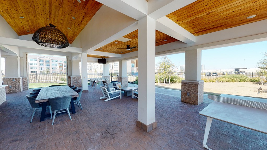 a covered patio with a wooden ceiling and brick flooring