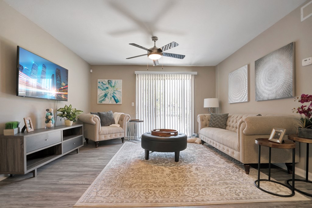 A living room with a flat screen TV mounted on the wall and a ceiling fan.