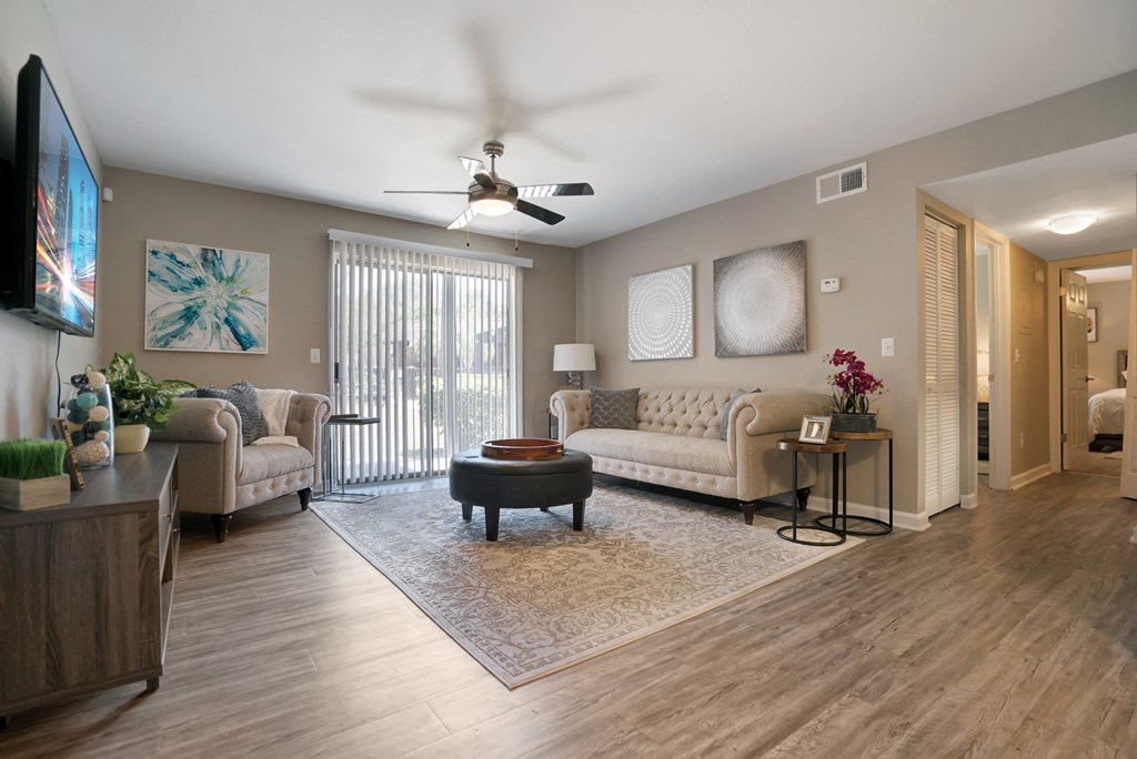 A living room with a white couch and a television on the wall.