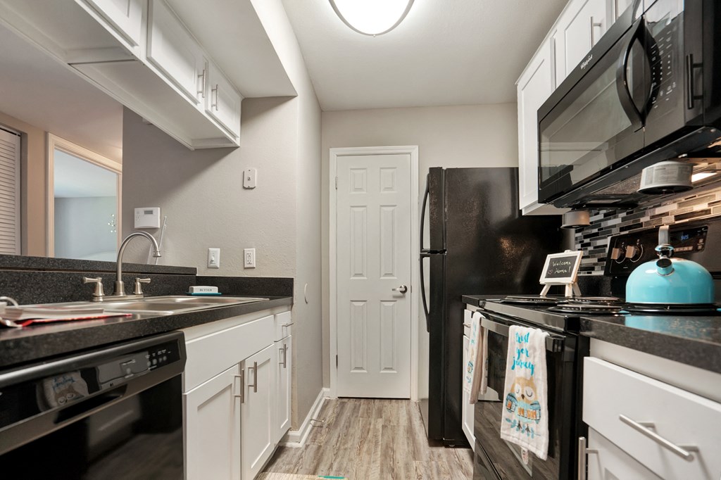 A kitchen with black appliances and white cabinets.