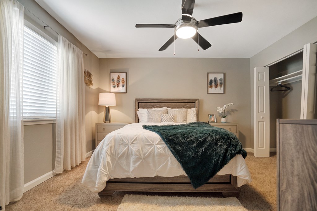 A bedroom with a bed, a ceiling fan, and a window with curtains.