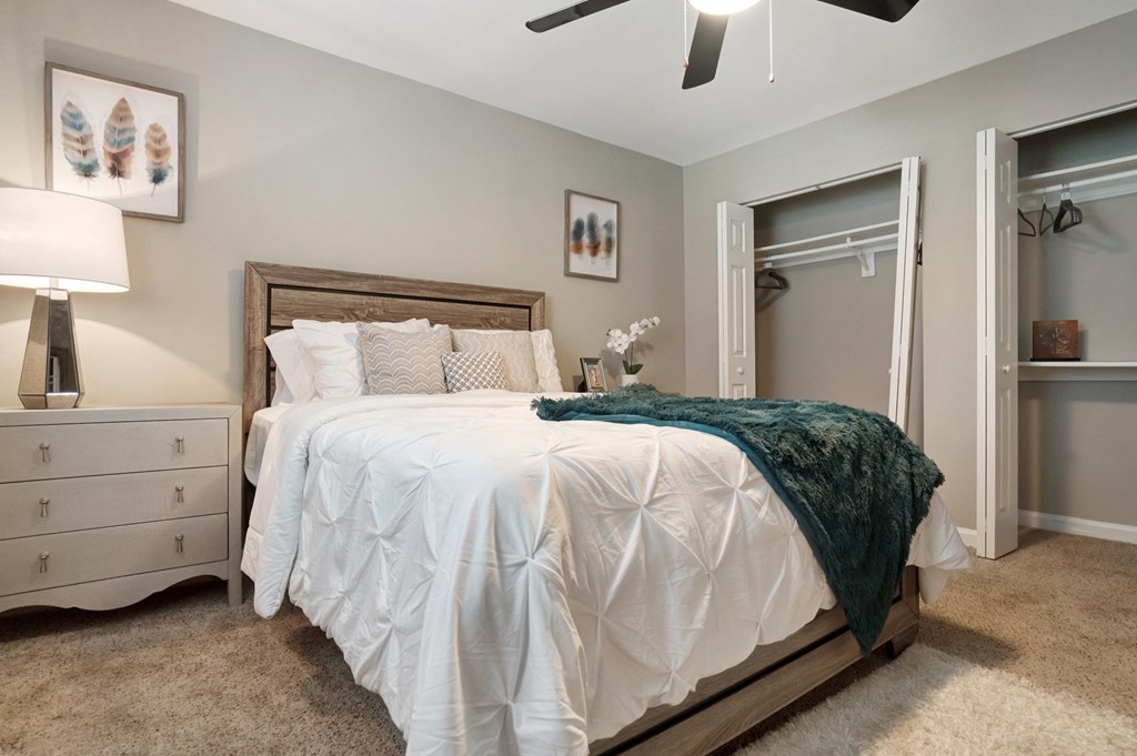 A bedroom with a white bed and a green throw blanket.
