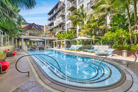 A large outdoor swimming pool surrounded by lounge chairs and umbrellas.
