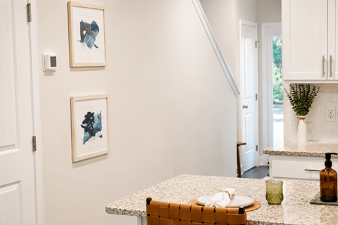 A kitchen with a white counter top and a painting on the wall.