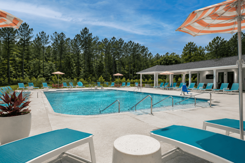 A pool with blue water and white lounge chairs.