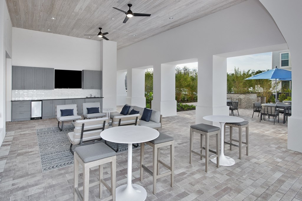 a rendering of a patio area with tables and chairs and a kitchen in the background