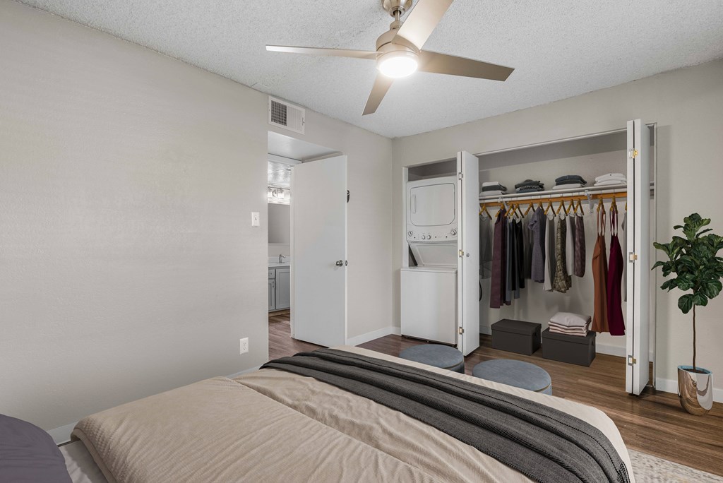 A bedroom with a bed, a ceiling fan, and a closet with clothes.