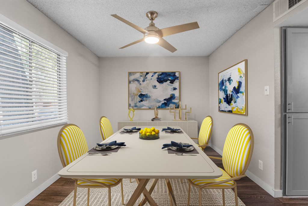 A dining room with a white table and yellow chairs.