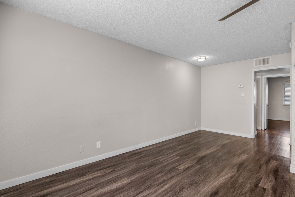 an empty living room with wood flooring and white walls