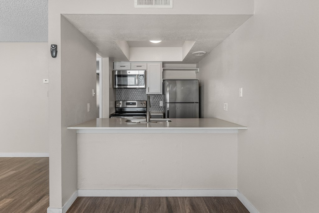 an empty kitchen with a counter top and a refrigerator and