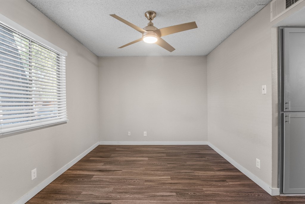 an empty room with a ceiling fan and a window