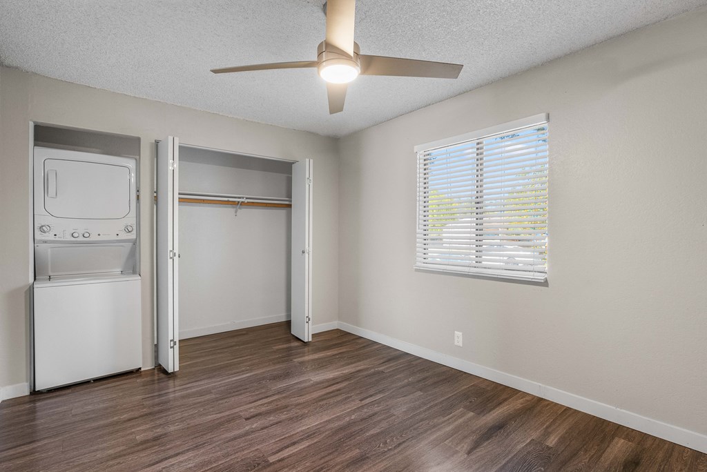 an empty living room with a ceiling fan and a laundry room