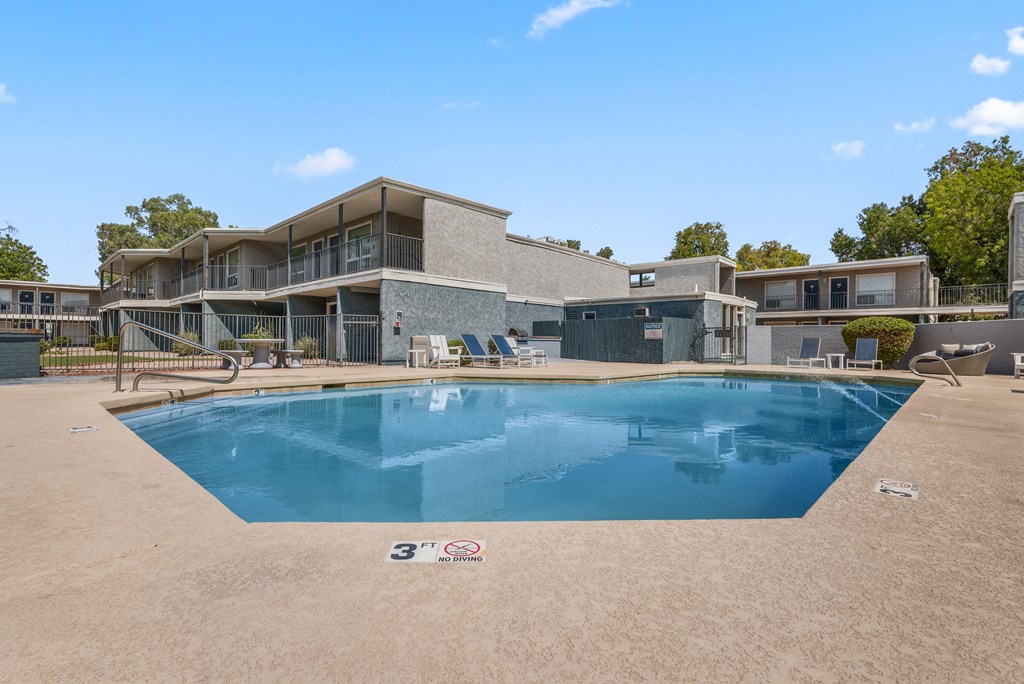 a swimming pool in front of a house with a building in the background