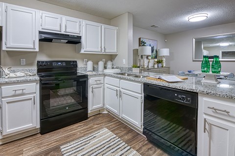 A kitchen with white cabinets and black appliances.