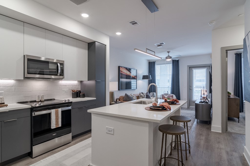 A modern kitchen with a white island and stainless steel appliances.