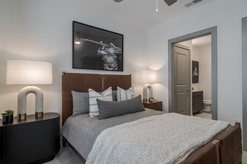 A bedroom with a bed, nightstand, and a painting on the wall.