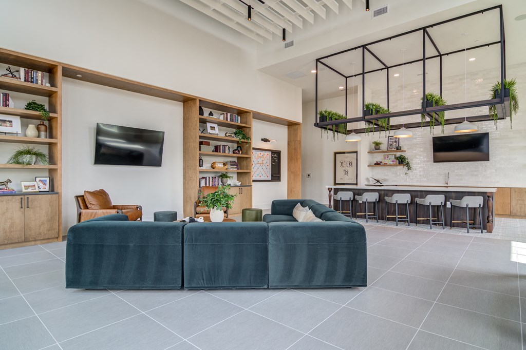 A living room with a green couch and a television on the wall.