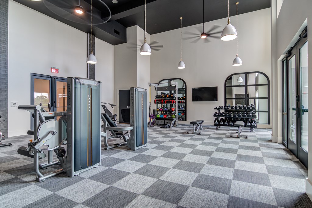 A gym with a variety of equipment including a weight machine, a treadmill, and a rowing machine.